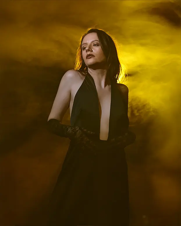 Umelecký portrét ženy fotený v ateliéri s dymom a farebným protisvcetlom